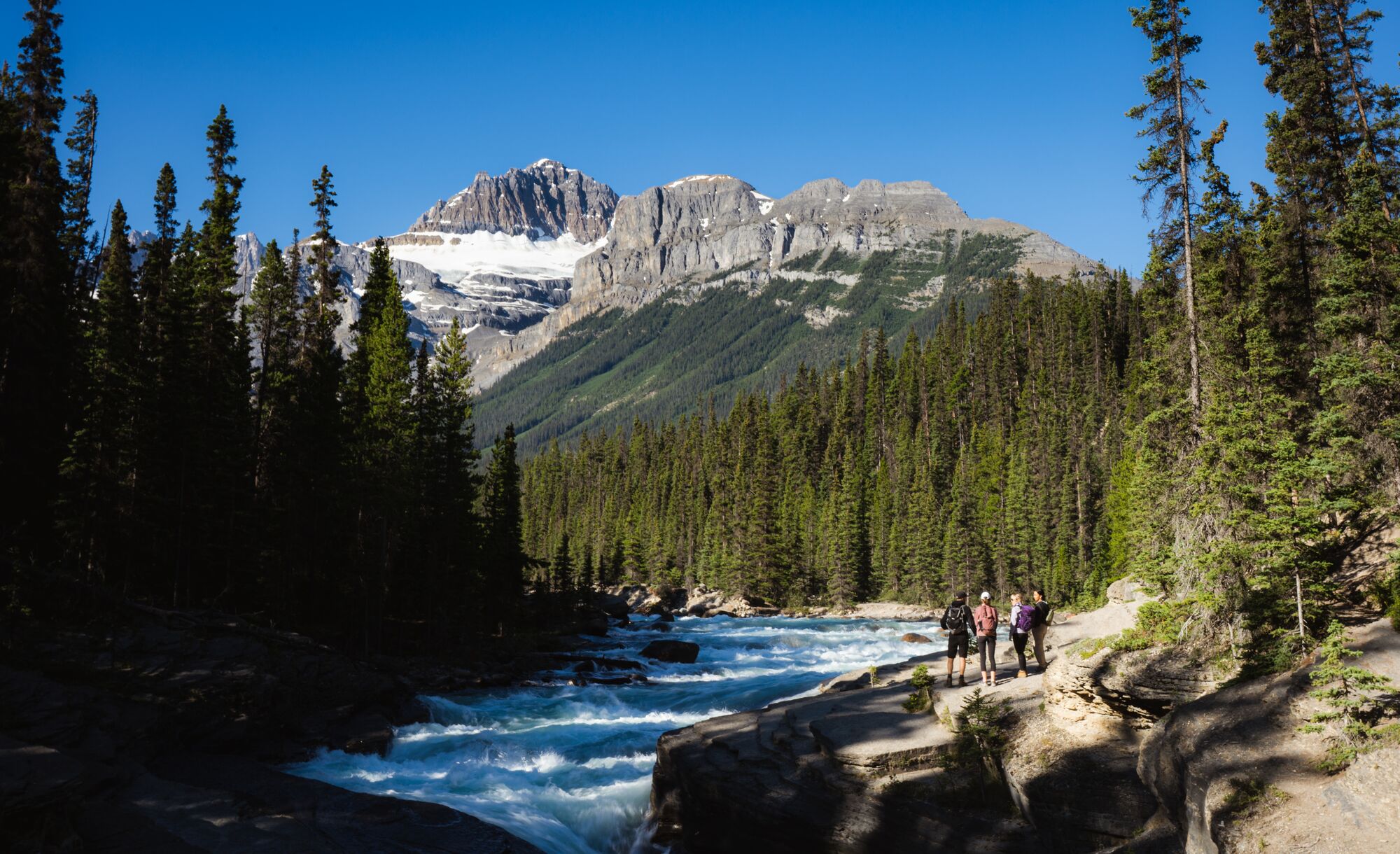 People stand overlooking the Mistaya Canyon waterfall on the Icefield Parkway in Banff National Park.